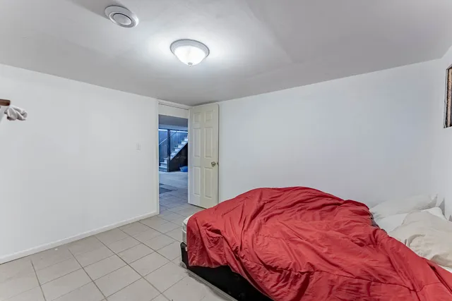 a bed sitting in a bedroom next to a window and a wooden floor
