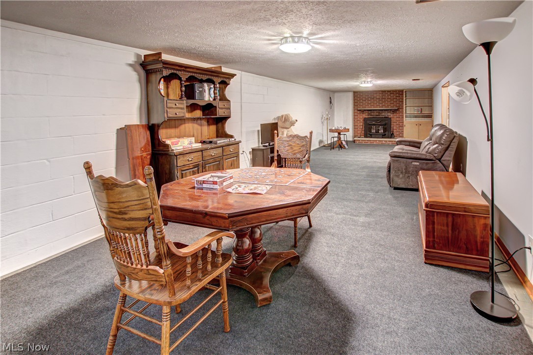 39974 Butternut Ridge Road Elyria, OH 44035 - Photo 30 of 40 Recreation room featuring dark colored carpet, a brick fireplace, and a textured ceiling