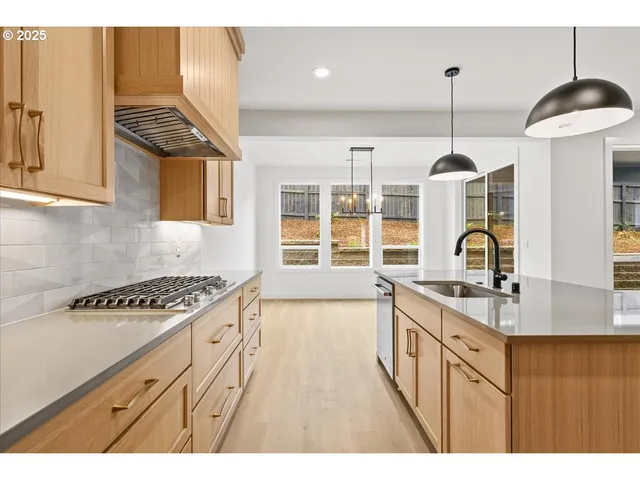 a kitchen with granite countertop a stove a sink a dining table and chairs