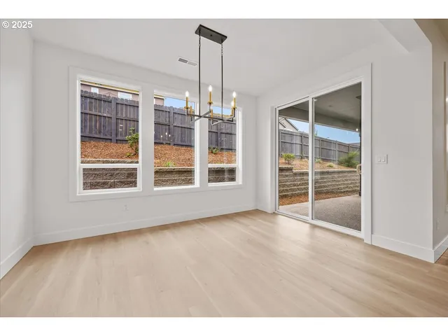 a view of an empty room with wooden floor and windows