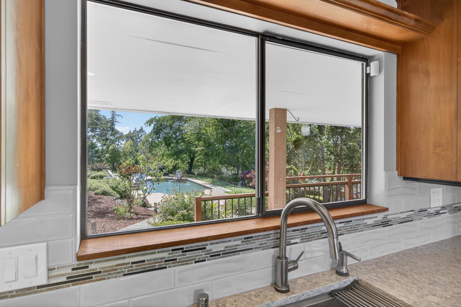 5560 Ralston Way Placerville, CA 95667 - Photo 20 of 78 Kitchen window overlooking a backyard with a swimming pool, mature trees, and landscaping