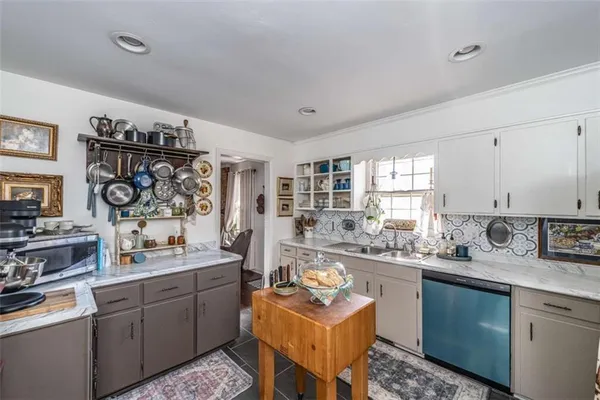 a kitchen with stainless steel appliances a sink a stove a window cabinets and a dining table
