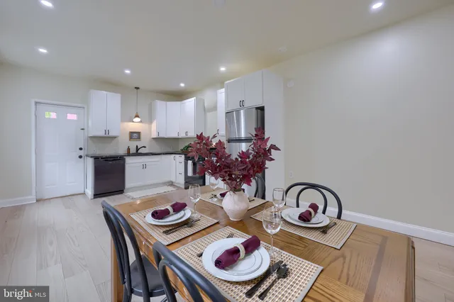 a kitchen with stainless steel appliances granite countertop a dining table and chairs with wooden floor