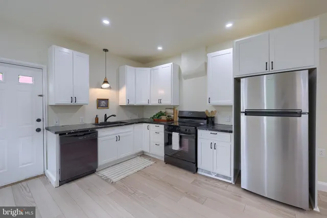 a kitchen with granite countertop a refrigerator stove top oven and sink