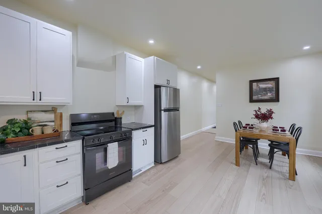 a kitchen with stainless steel appliances wooden floor and chairs