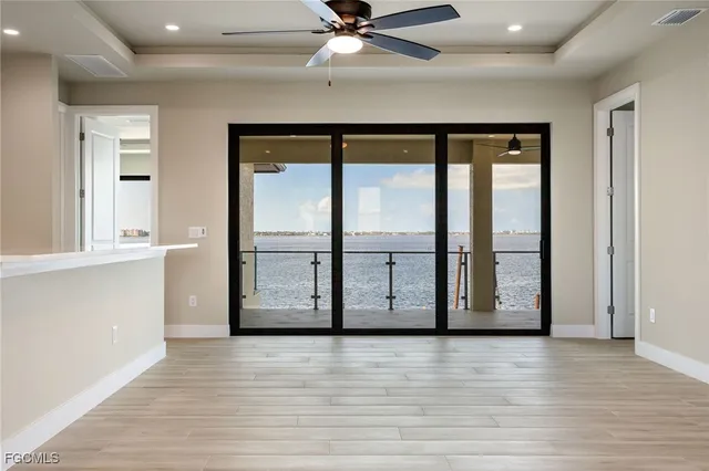 an empty room with wooden floor fan and windows