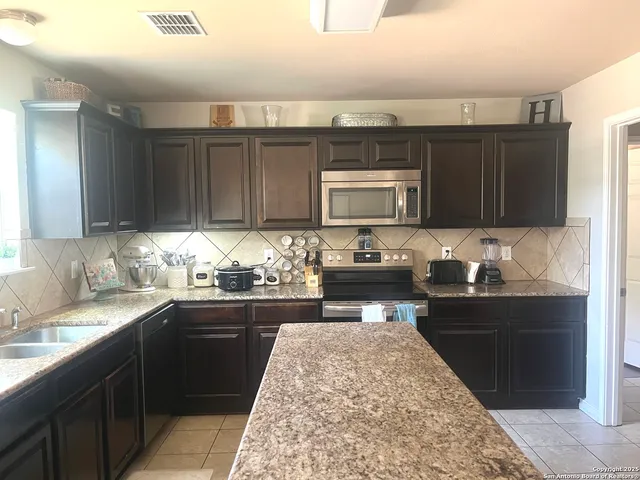 a kitchen with granite countertop a sink and a stove top oven