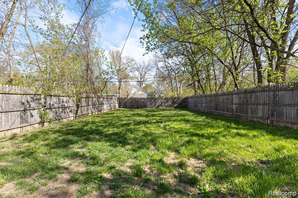 26076 Colgate Street Inkster, MI 48141 - Photo 23 of 24 Fenced backyard featuring natural wood privacy fencing, a level grass lawn, and mature trees surrounding the perimeter