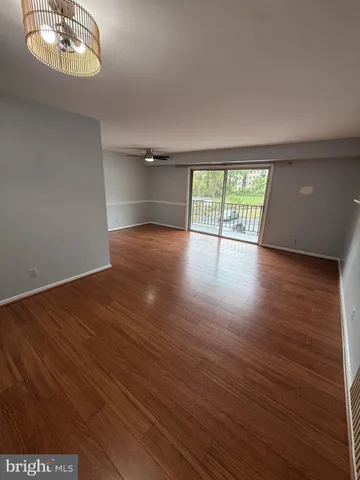 an empty room with wooden floor chandelier and windows