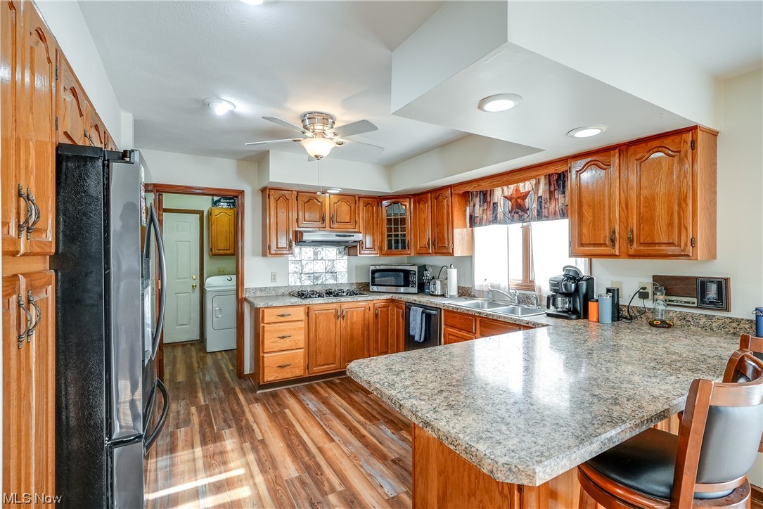 13920 Kneisel Road Vermilion, OH 44089 - Photo 9 of 35 Kitchen with a kitchen breakfast bar, appliances with stainless steel finishes, kitchen peninsula, ceiling fan, and hardwood / wood-style floors