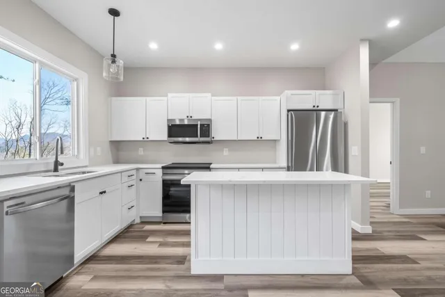 a kitchen with kitchen island a sink stainless steel appliances and cabinets