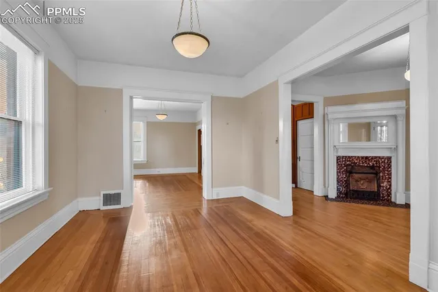 a view of an empty room with wooden floor and a window