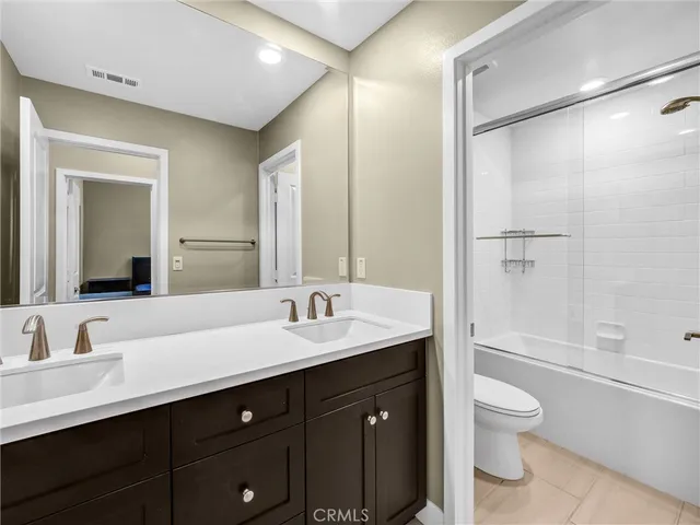 a bathroom with a granite countertop sink toilet a large mirror a shower and a bathtub