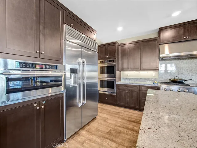 a kitchen with stainless steel appliances granite countertop a refrigerator a stove and a sink