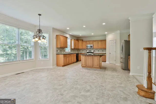 a kitchen with stainless steel appliances granite countertop a stove a sink and a refrigerator with white cabinets