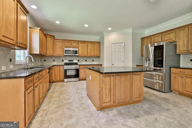 a large kitchen with stainless steel appliances granite countertop a sink counter space cabinets and a large window