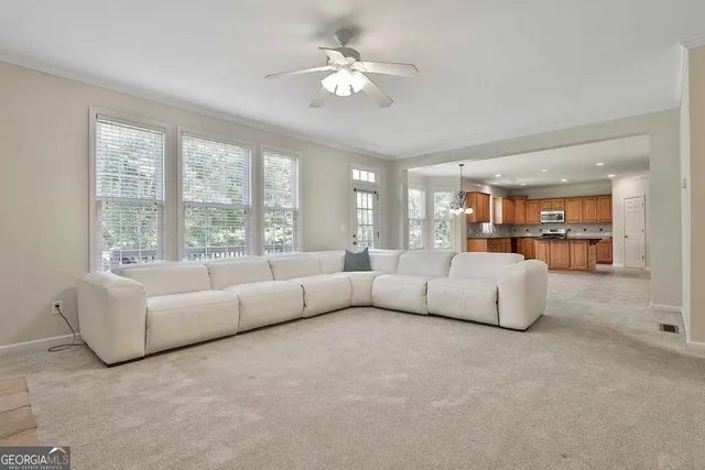 an empty room with windows and chandelier fan