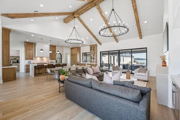 a living room with furniture kitchen view and a chandelier