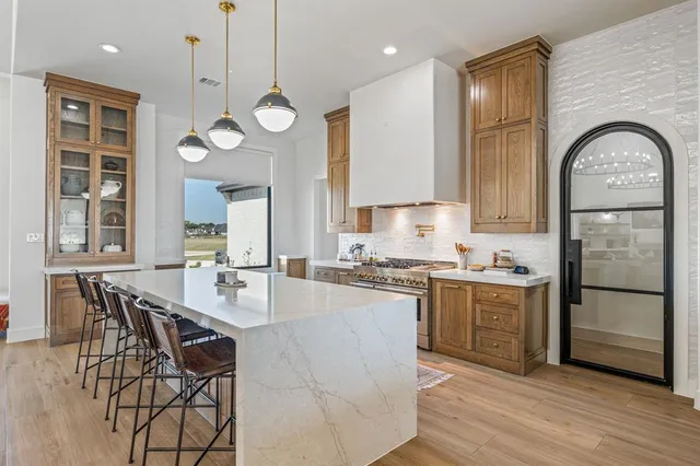 a kitchen with stainless steel appliances granite countertop a stove a sink a refrigerator cabinets and dining table with wooden floor