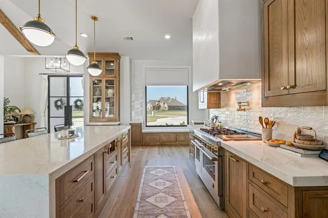 a kitchen with stainless steel appliances granite countertop a sink a stove and a wooden cabinets