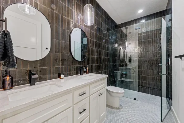 a bathroom with a double vanity sink toilet mirror and shower