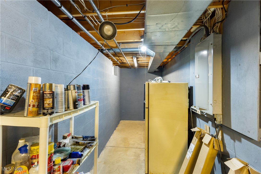 7665 Brakeman Road Painesville, OH 44077 - Photo 27 of 34 Unfinished basement with electric panel, freestanding refrigerator, and concrete block wall