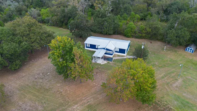 an aerial view of a house with a yard and trees all around