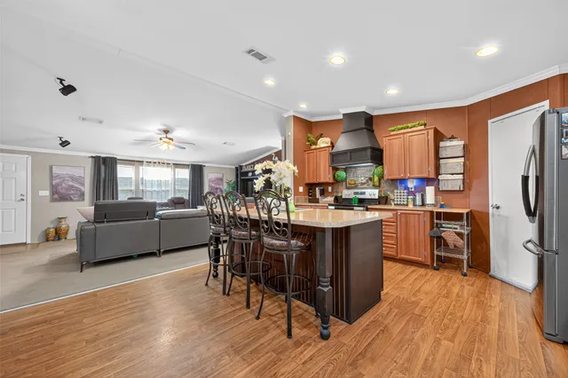 a kitchen with stainless steel appliances granite countertop a refrigerator a sink dishwasher a dining table and chairs with wooden floor