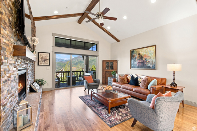 5207 North Oldgate Road Heber City, UT 84032 - Photo 7 of 58 Vaulted ceilings with exposed wood beams, a stone-clad fireplace, wood-finish flooring, and a sliding glass door leading to an outdoor deck