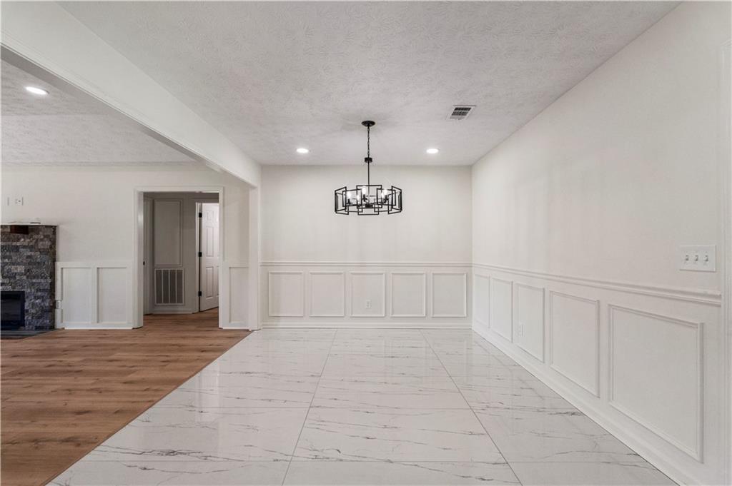 766 Lee Road Phenix City, AL 36870 - Photo 7 of 30 Corridor with light marble finish flooring, a decorative wall, recessed lighting, a wainscoted wall, and a chandelier
