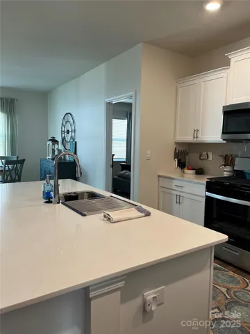 a kitchen with sink a stove and white cabinets