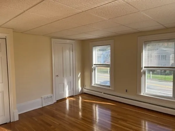 an empty room with wooden floor and windows with curtains