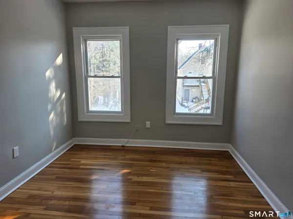 a view of an empty room with wooden floor and a window