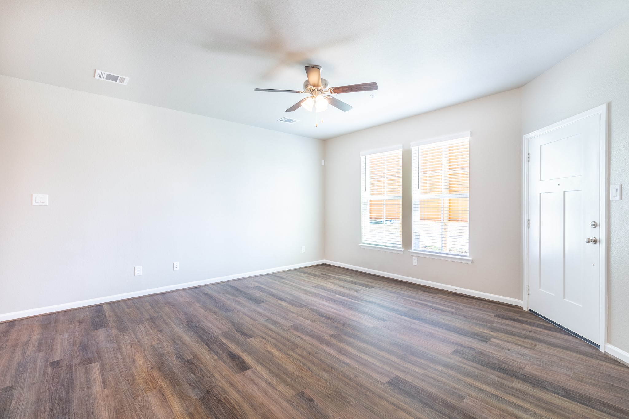 115 Park Place Circle, Unit B Waller, TX 77484 - Photo 19 of 24 an empty room with wooden floor chandelier fan and windows