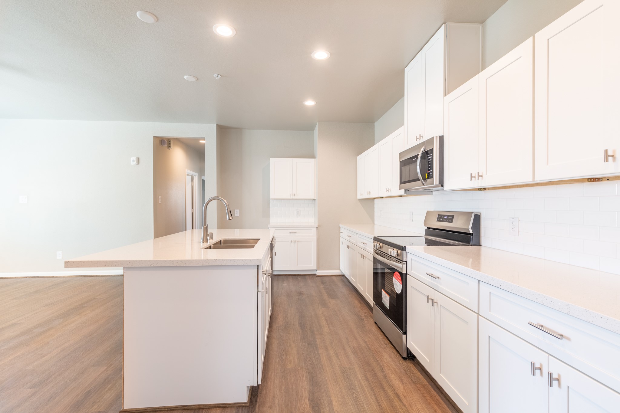 115 Park Place Circle, Unit B Waller, TX 77484 - Photo 9 of 24 a kitchen with stainless steel appliances granite countertop a stove top oven a sink dishwasher and a refrigerator with wooden floor