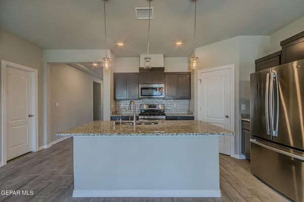 a large kitchen with kitchen island a large counter top stainless steel appliances and cabinets