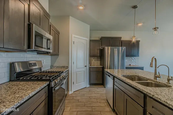 a kitchen with stainless steel appliances granite countertop a sink stove and refrigerator