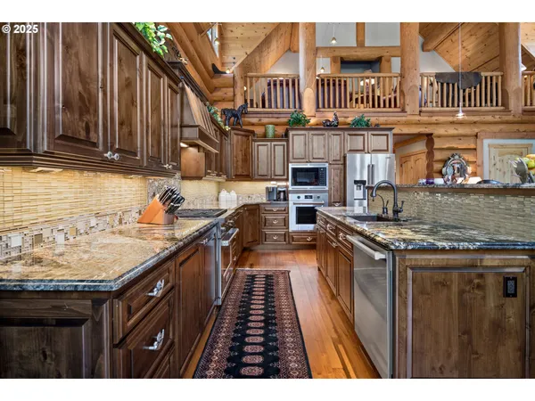 a kitchen with stainless steel appliances granite countertop a stove a sink dishwasher and cabinets with wooden floor