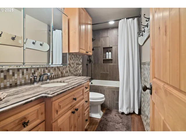 a bathroom with a granite countertop sink a toilet a mirror and shower