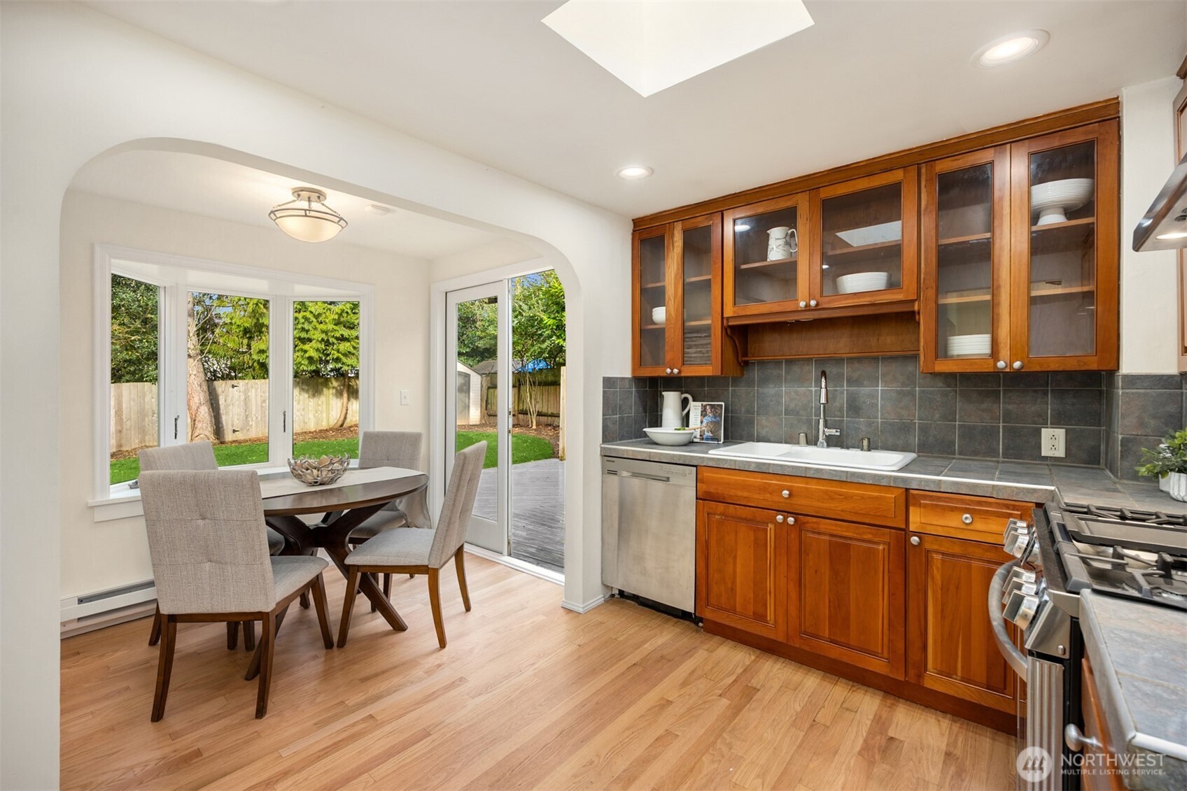 5606 Northeast 59th Street Seattle, WA 98105 - Photo 11 of 28 a dining room with stainless steel appliances granite countertop a stove a kitchen island a dining table and chairs with wooden floor