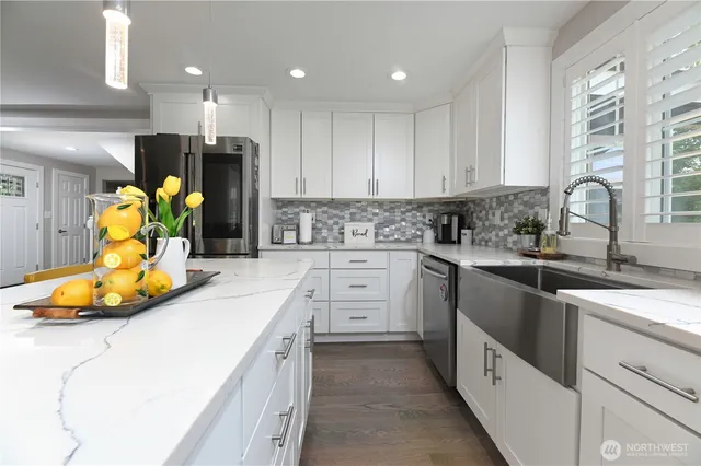 a kitchen that has a lot of white cabinets and stainless steel appliances