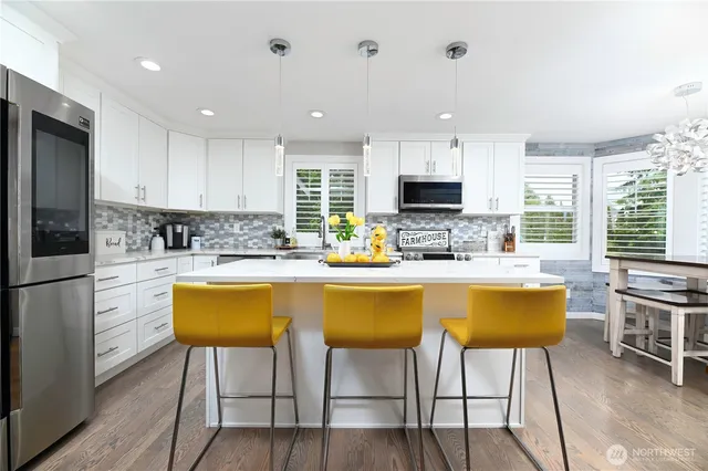 a kitchen with stainless steel appliances granite countertop a stove a sink a microwave a dining table and chairs