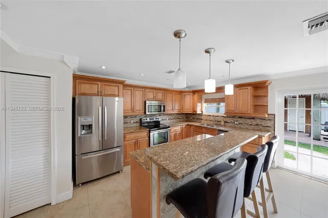 a kitchen with stainless steel appliances kitchen island granite countertop a stove a sink a dining table and chairs