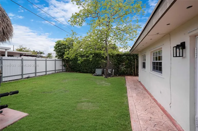 a view of backyard of house with wooden fence