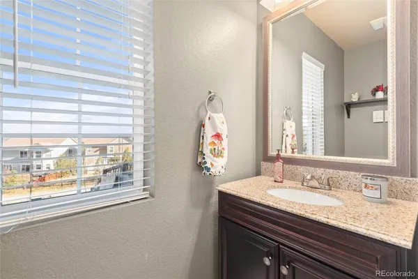 a bathroom with a granite countertop sink and a large mirror
