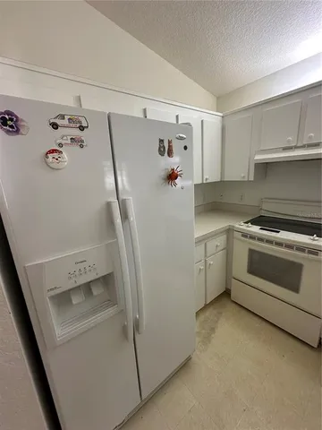 a view of a kitchen with white cabinets and white appliances
