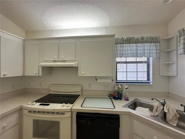 a kitchen with a sink stove top oven and cabinets