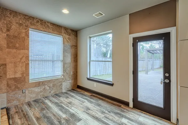 a view of an empty room with window and wooden floor