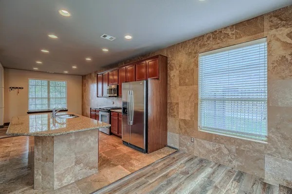 a view of a hallway with wooden floor and a kitchen