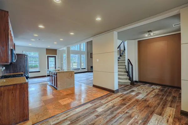 a large kitchen with stainless steel appliances granite countertop a stove top oven a sink dishwasher a dining table and chairs with wooden floor